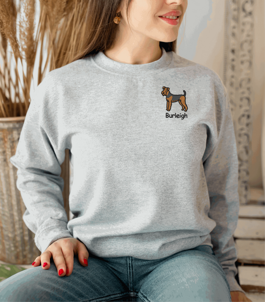 a woman sitting on a chair wearing a grey sweatshirt with a dog embroidered on the