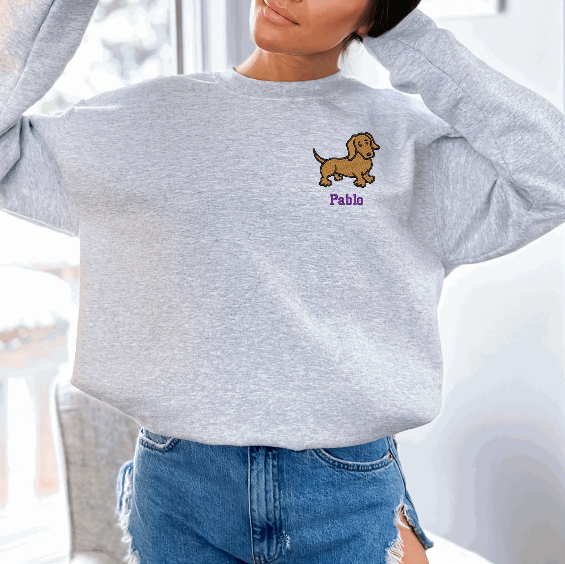 a woman wearing a sweatshirt with a dog embroidered on it