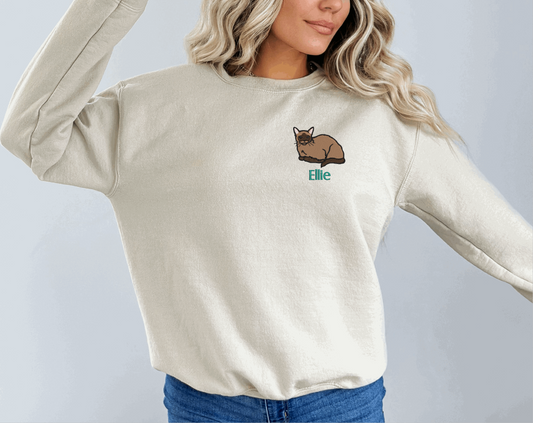 a woman wearing a white sweater with a cat embroidered on it