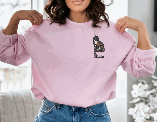 a woman wearing a pink sweatshirt with a cat embroidered on it