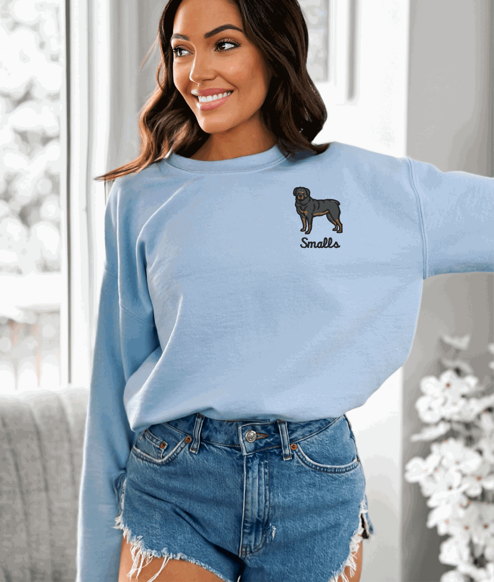 a woman wearing a light blue sweater with a dog embroidered on it