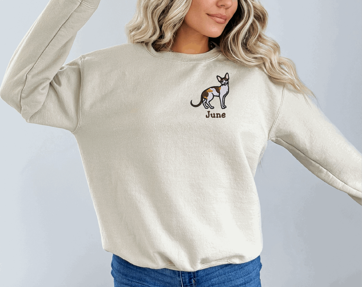 a woman wearing a white sweatshirt with a dog embroidered on it